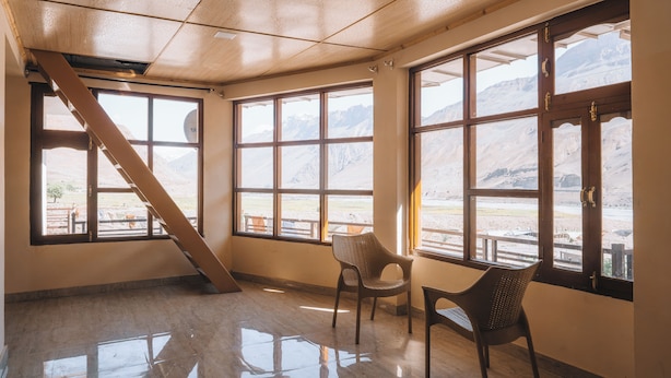 A room with large windows, a wooden ceiling, and a view of mountains. - Spiti Heritage (Spiti)