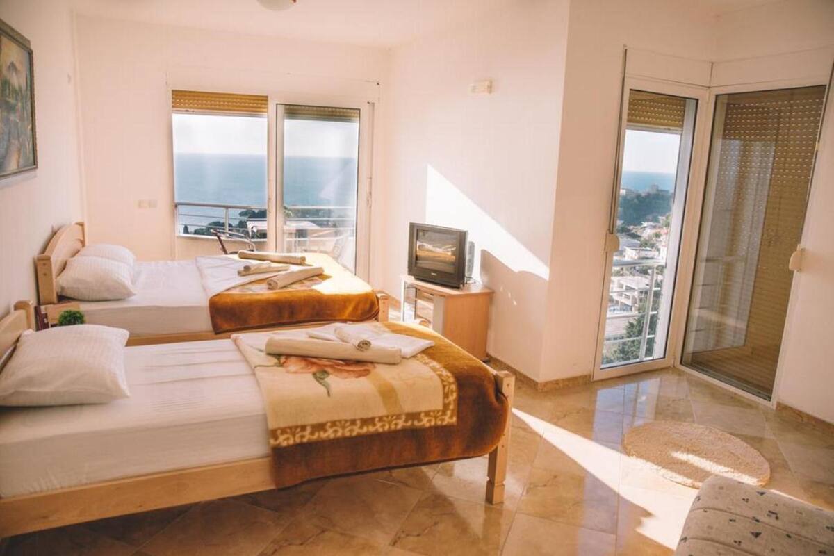 Une chambre d’hôtel avec deux lits, une télévision et une vue sur la ville et la mer.