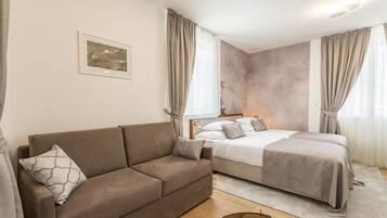 Ett sovrum med en soffa, en säng, en sänggavel och ett fönster med gardiner.