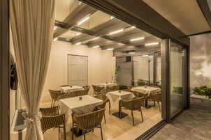 An indoor dining area with tables and chairs, a glass partition, and a view of the outdoors.