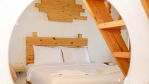 Camera da letto con testiera in legno, biancheria bianca e decorazione murale in legno.