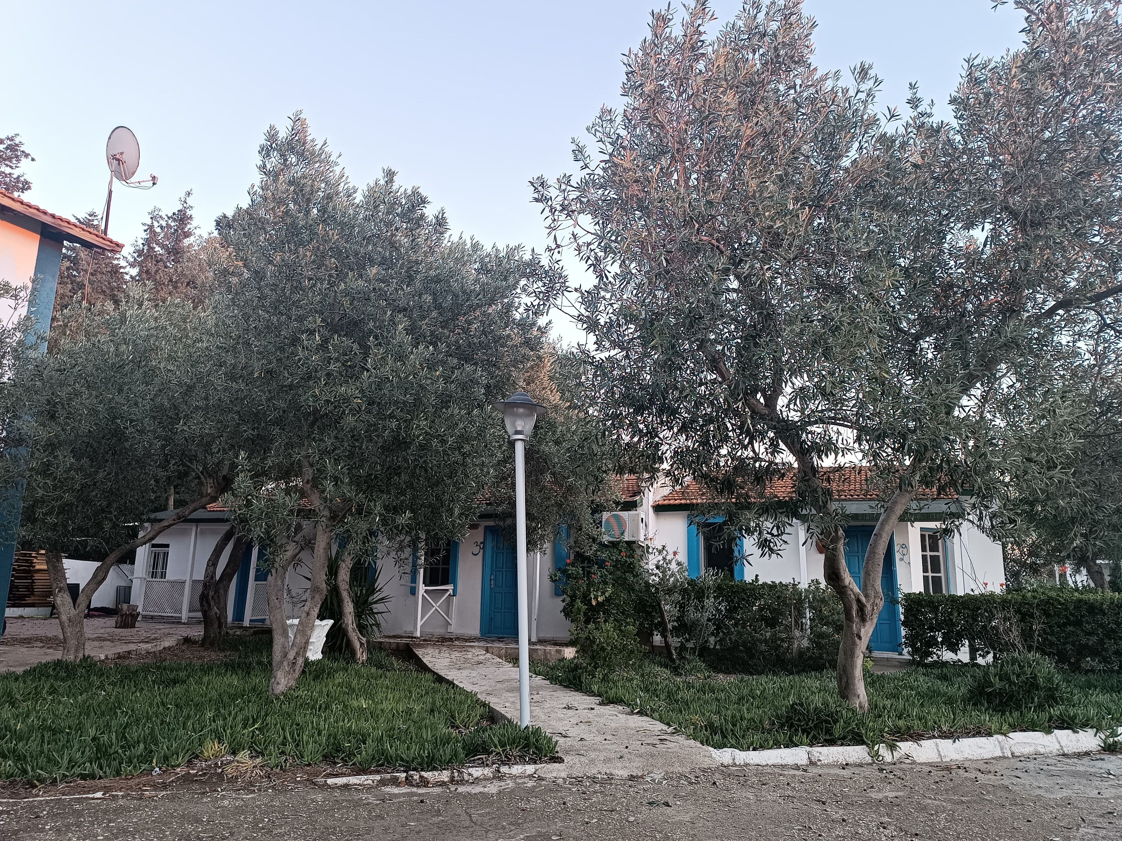 Un quartier résidentiel avec un immeuble blanc orné de motifs bleus, une antenne parabolique et un lampadaire.