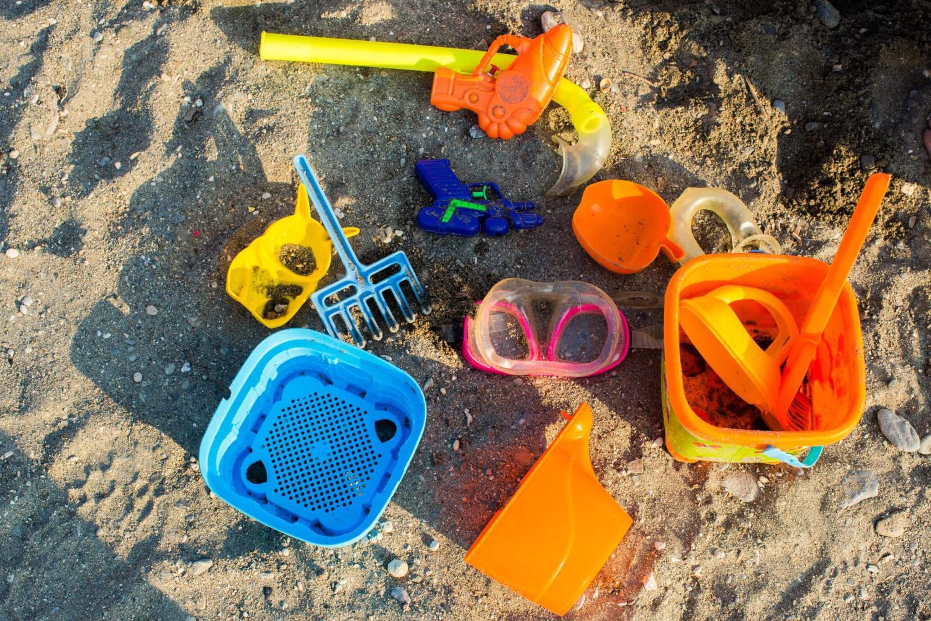 De nombreux jouets de plage sont éparpillés sur le sable.