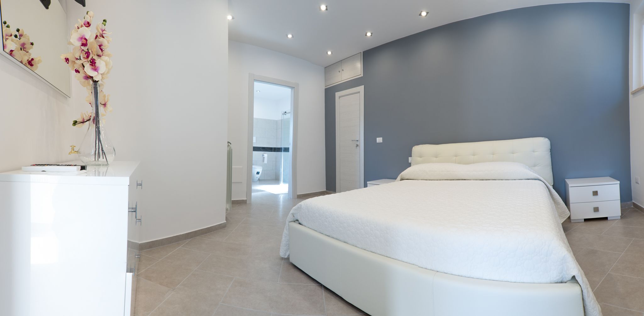 Un dormitorio moderno con una cama grande, una mesita de noche y un aparador.