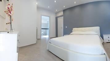 Un dormitorio moderno con una cama grande, una mesita de noche y un aparador.