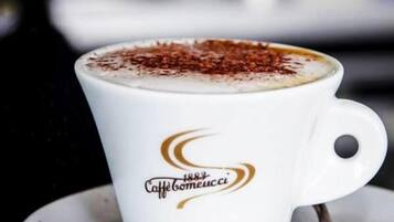 A white cup with a logo and text on it, placed on a saucer.
