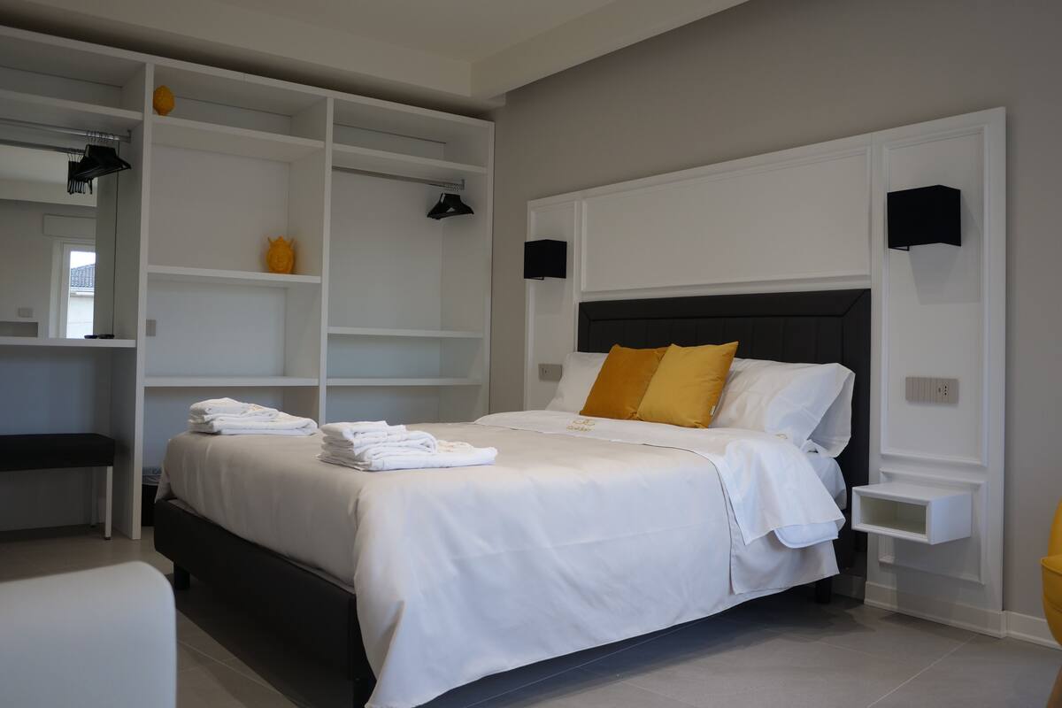 A modern bedroom with a large bed, built-in shelving, and a bedside table.
