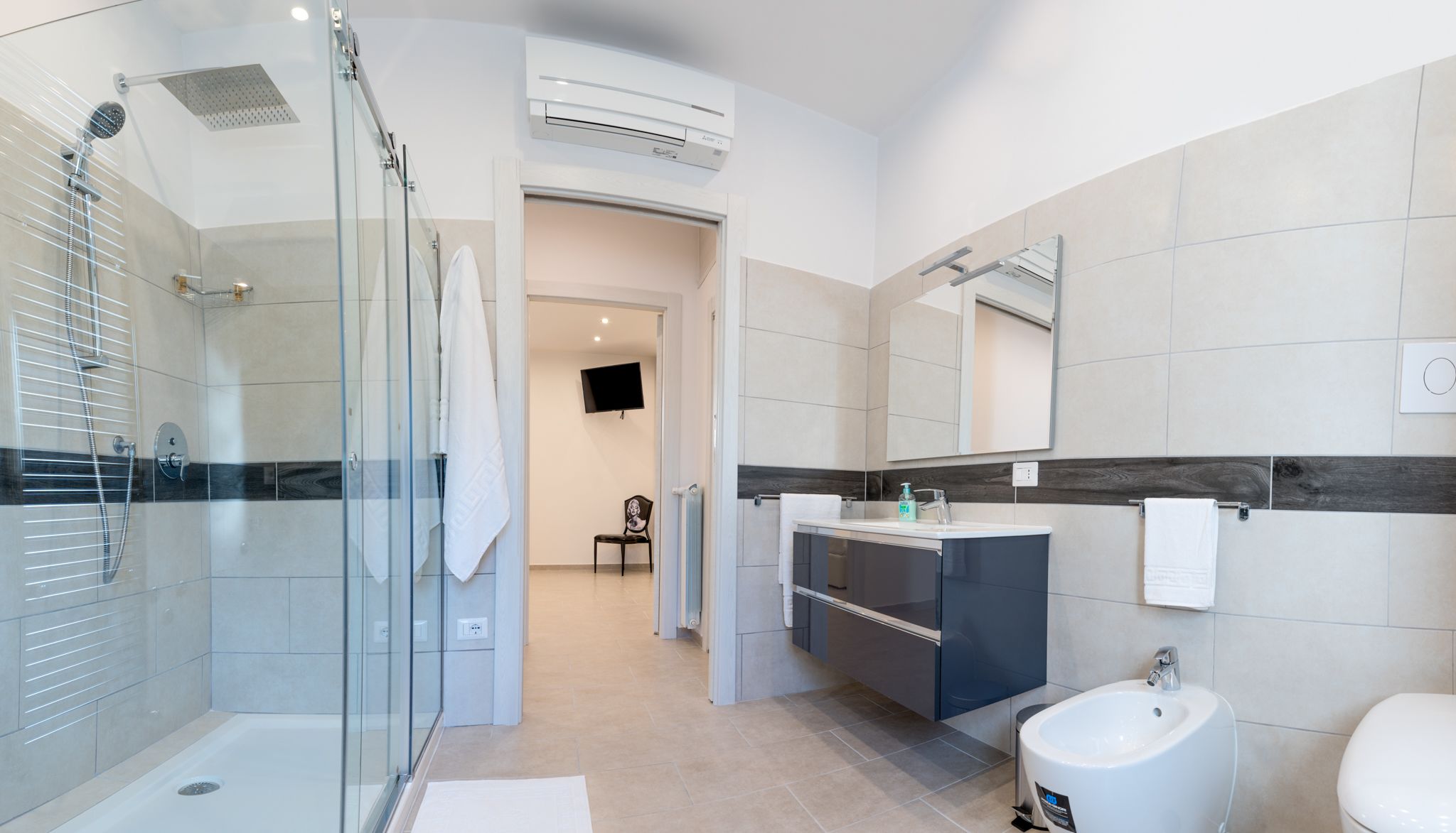 Une salle de bain moderne avec une douche à l’italienne en verre, un meuble-lavabo avec un miroir et un bidet.