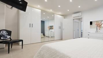 Quarto moderno com cama, uma cadeira, televisão e guarda-roupa com espelho.