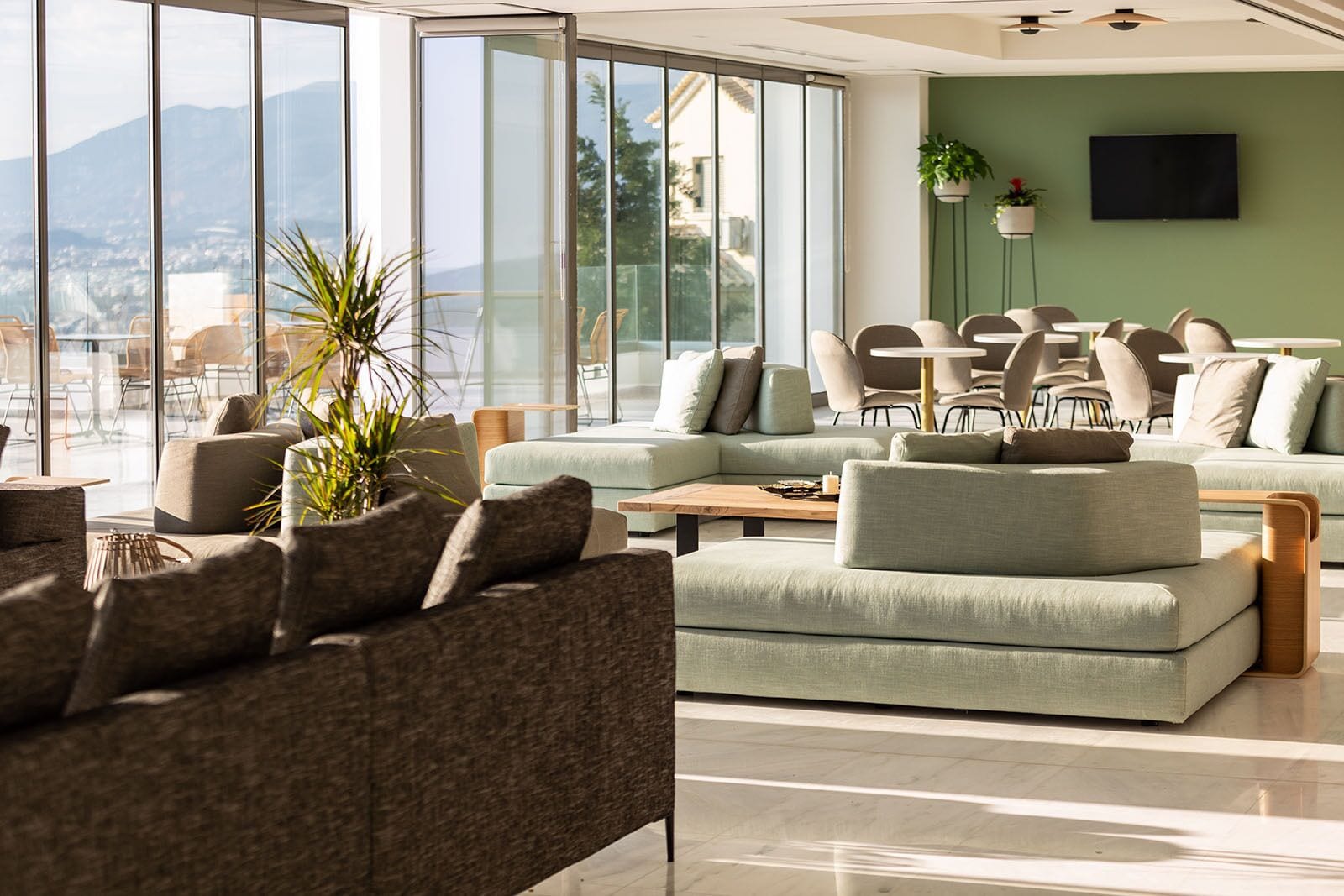A modern living room with a large window, a sofa, a coffee table, and a TV.