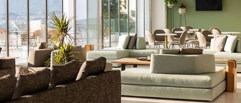 A modern living room with a large window, a sofa, a coffee table, and a TV.