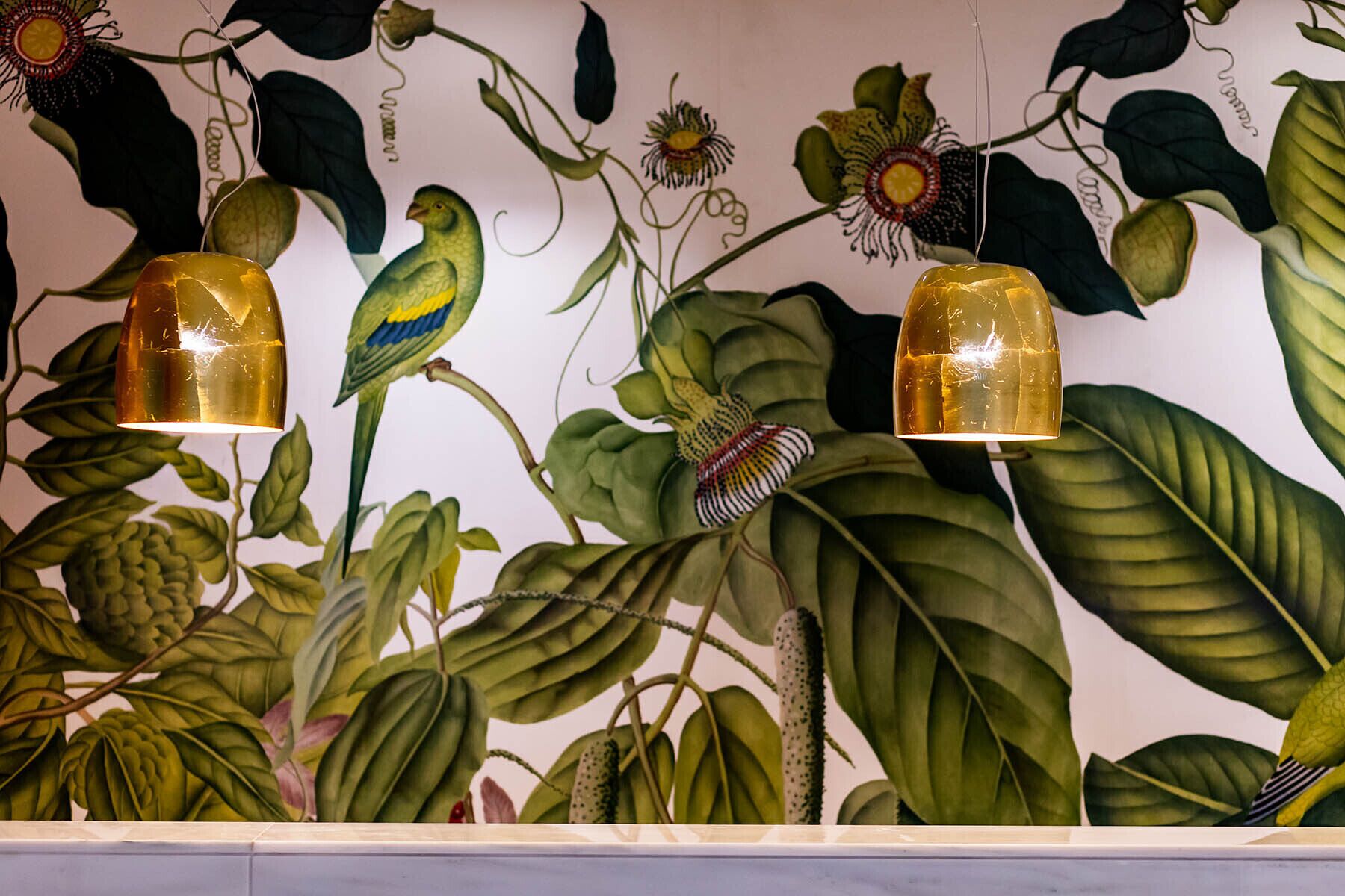 A wall with a botanical mural featuring large leaves and hanging plants.