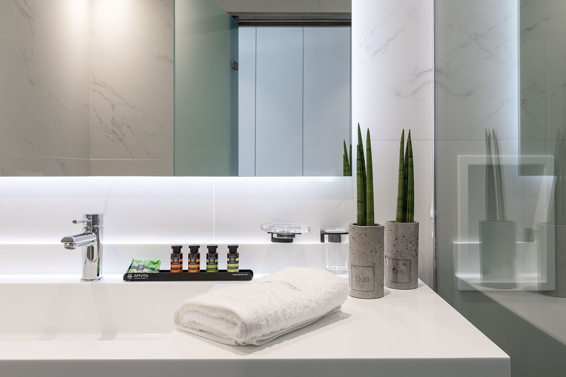 A modern bathroom with a white sink, a mirror, and a glass shower enclosure.