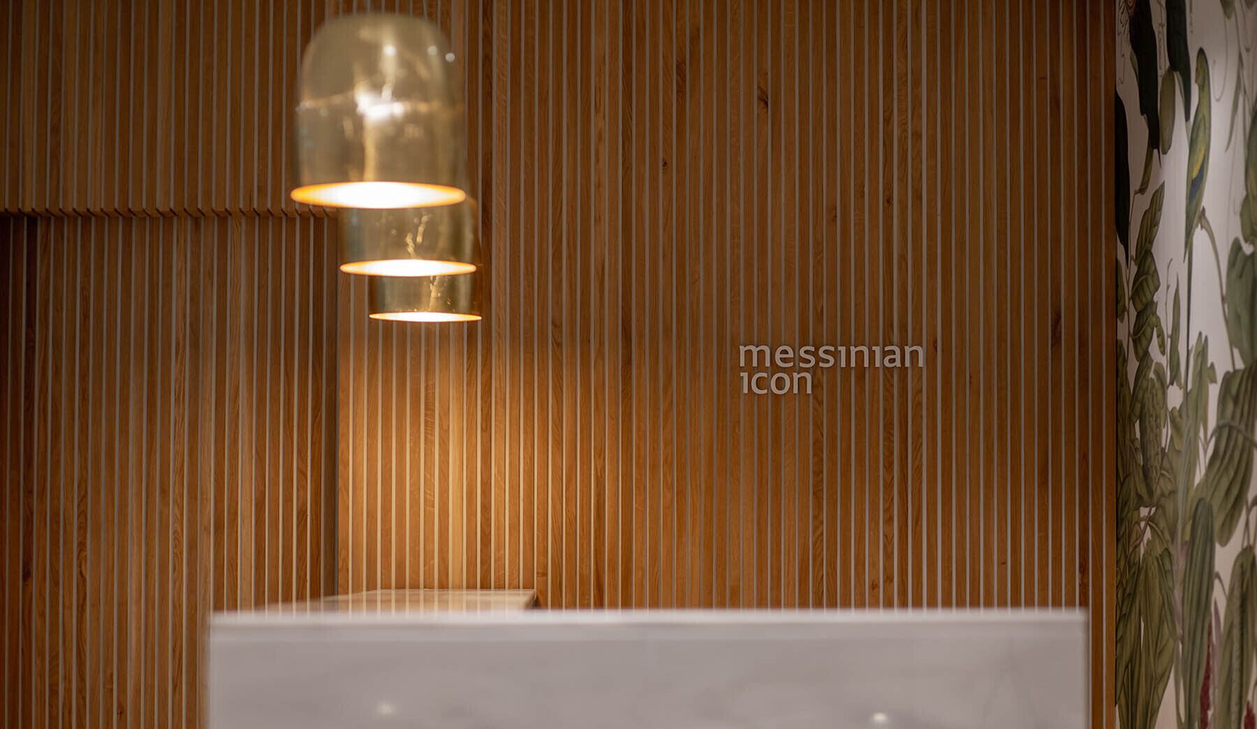Un baño con paneles de madera verticales, una lámpara moderna y una bañera blanca.