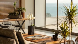 Un salon moderne avec une table basse en bois, des chaises en fil de fer noir et des plantes en pot.