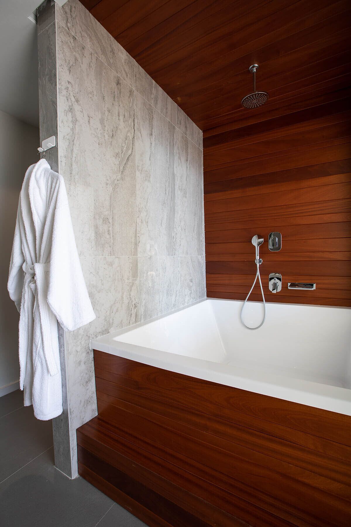Un baño moderno con una bañera grande, paneles de madera y un cabezal de ducha.