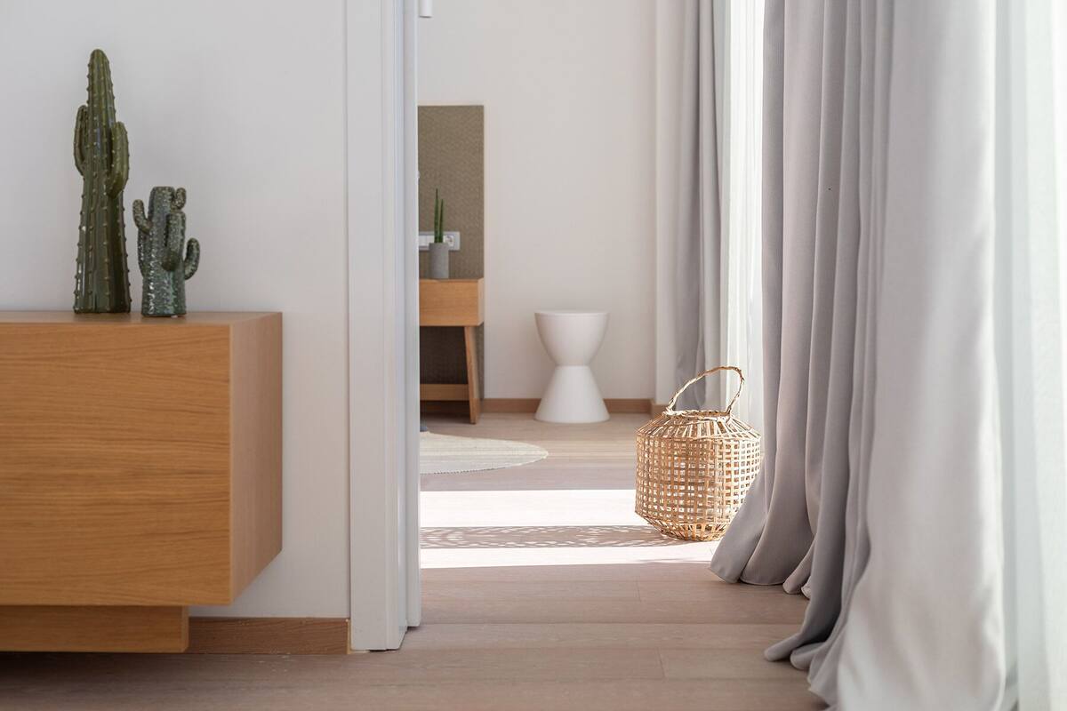 A modern interior with a wooden console, a wicker basket, and a minimalist bathroom.