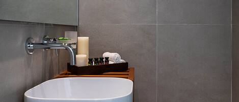 A modern bathroom with a large white sink, a mirror above it, and a wooden vanity.