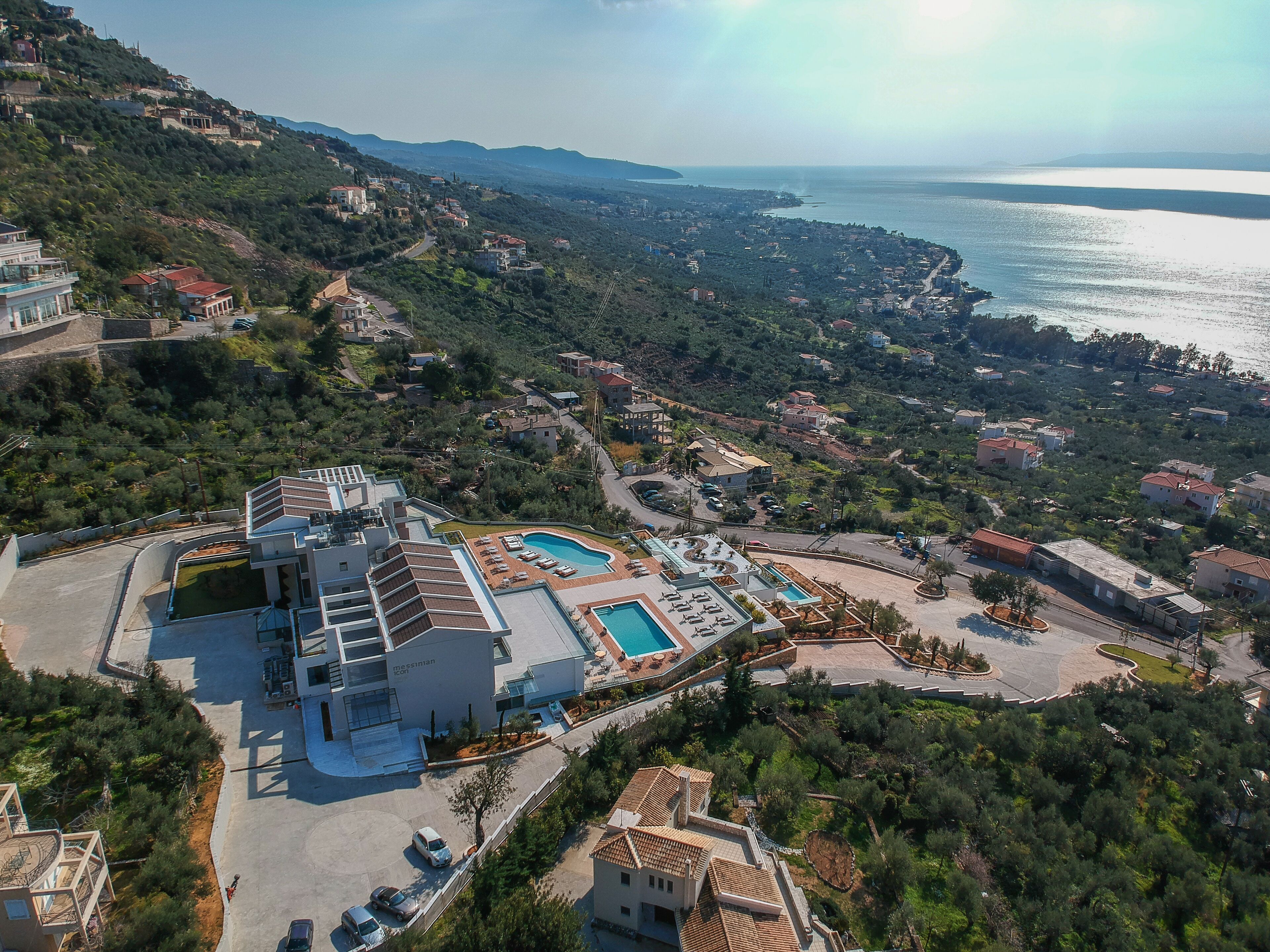 A resort with multiple swimming pools, a large parking area, and a view of the sea.