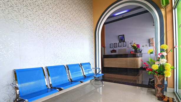 A reception area with a blue bench, a reception desk, and a vase of flowers.
