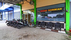 A motorcycle repair shop with several motorcycles parked outside and a row of chairs in front of the entrance.