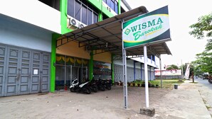 A building with a sign reading "WISMA Barokah" and a row of motorcycles parked outside.
