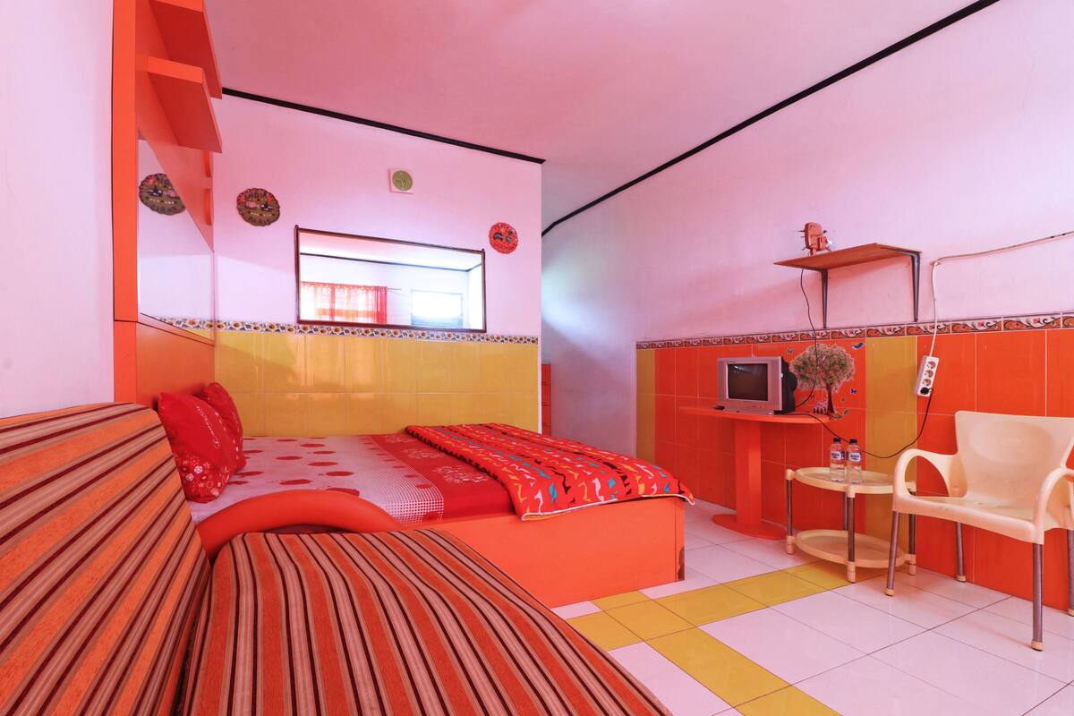 A room with a bed, a small desk with a TV, and a chair.