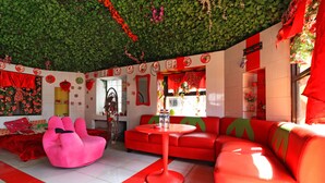 A vibrant room with a green leafy ceiling, red and white walls, and a red sofa. - Hotel Agung Permata Artha (Garut)