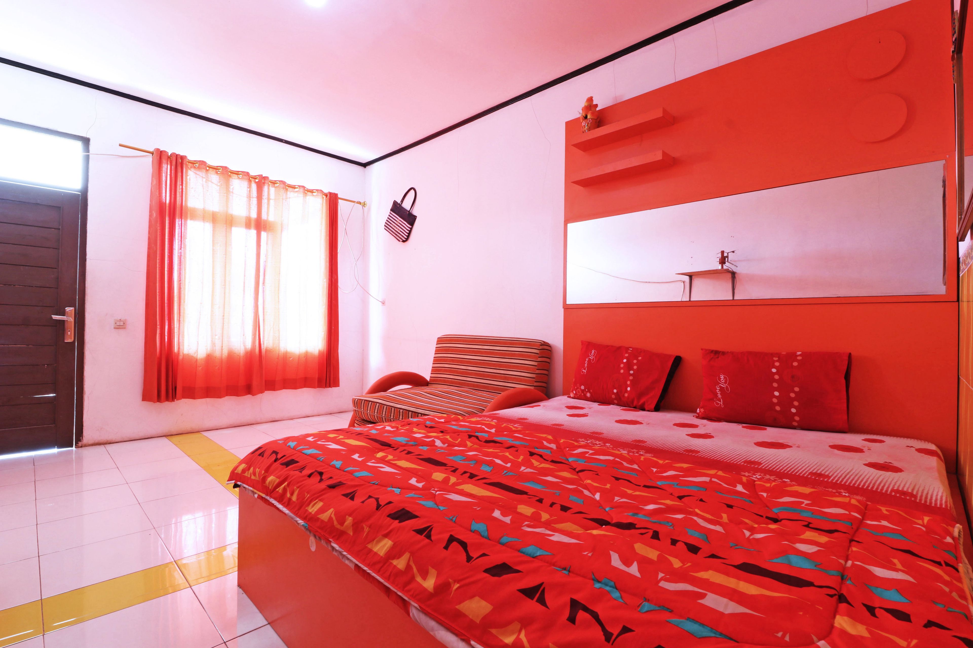 Un dormitorio con una cama grande, una silla, una mesita de noche y una ventana con cortinas.