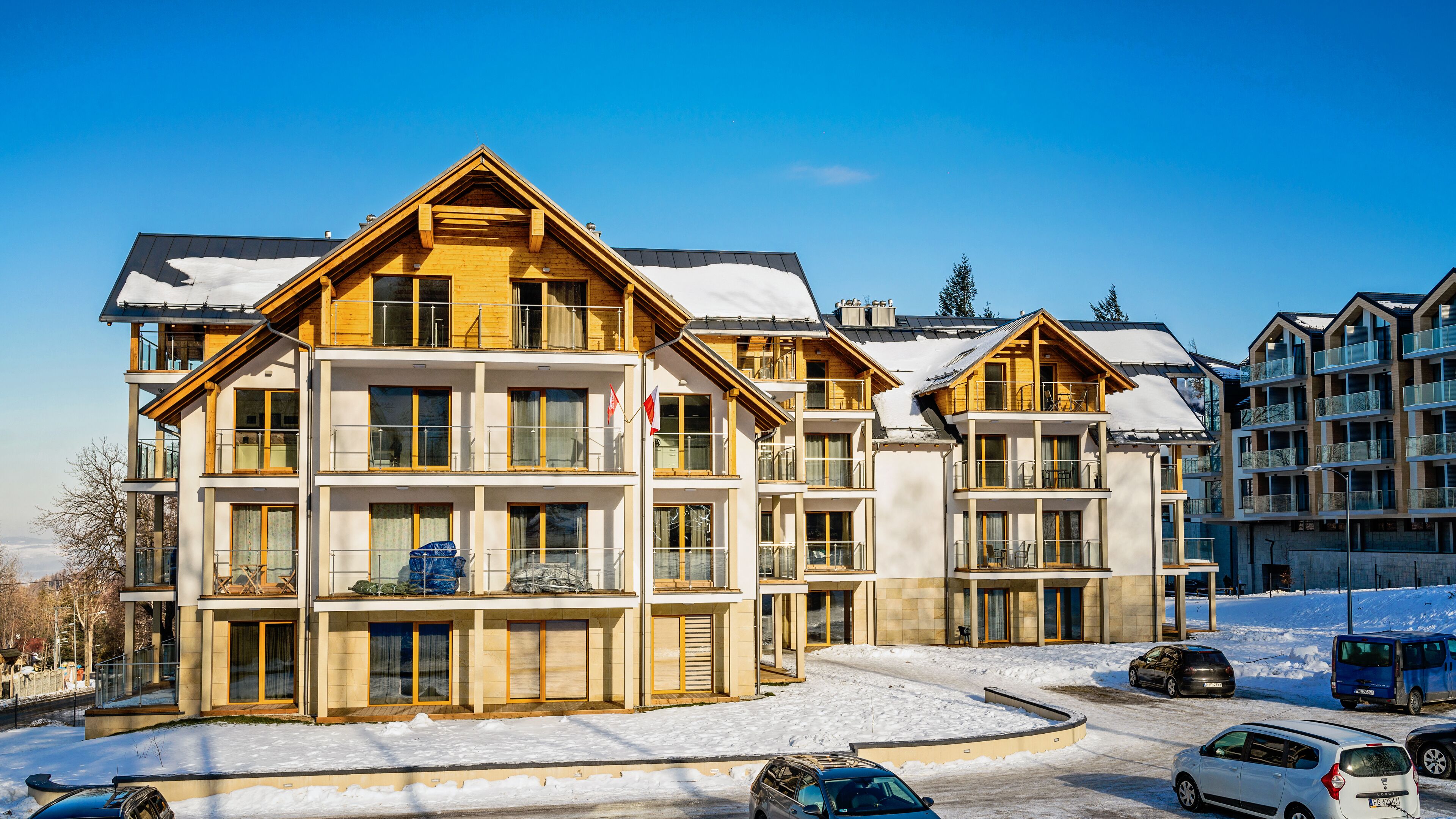 A multi-story hotel with balconies, large windows, and a snow-covered ground.