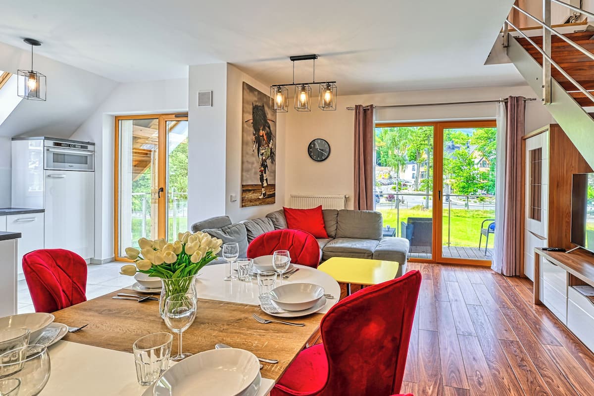 A modern kitchen with a dining area, a staircase, and a view of the outdoors.