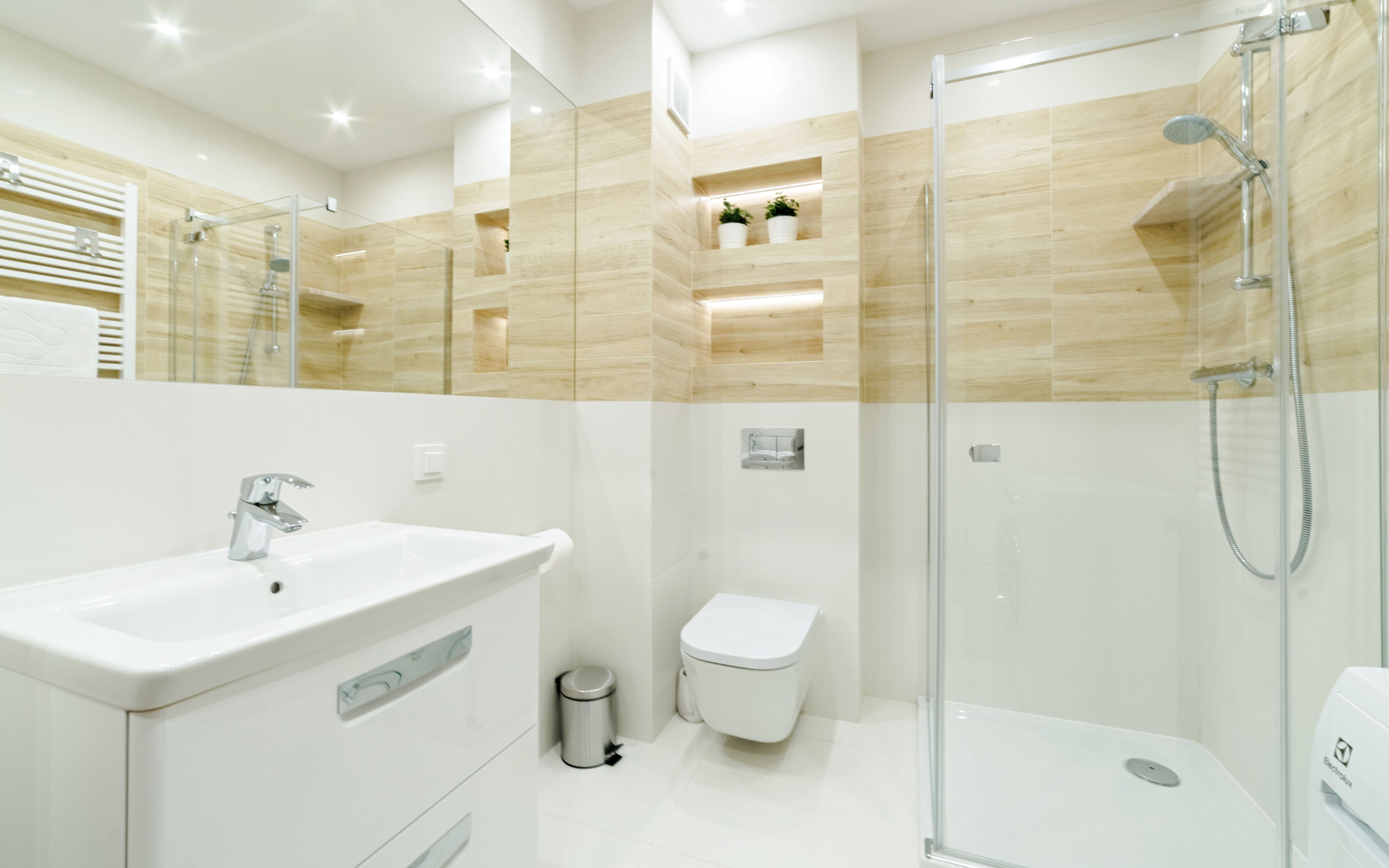 Une salle de bain moderne avec une douche à parois de verre, un lavabo blanc et des toilettes.