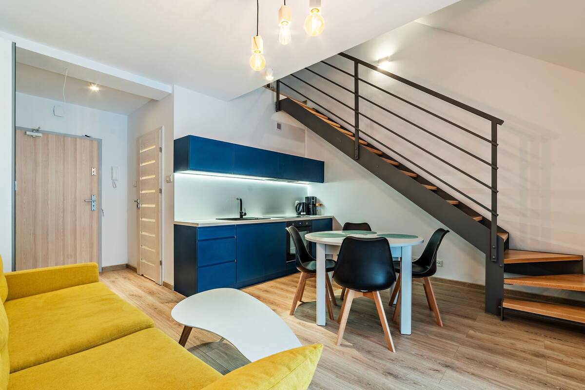 A modern apartment with a kitchen, dining area, and a staircase.