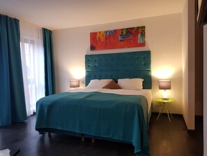 Relax in comfort with a large bed, two bedside tables, and a colorful abstract painting.