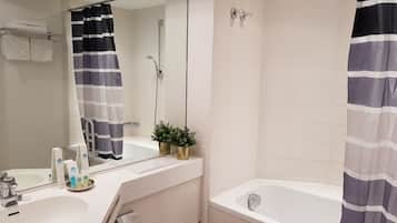 A bathroom with a sink, mirror, toilet, bathtub, and shower curtain.