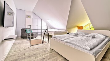Un dormitorio moderno con techo estilo loft, una cama, un sofá y un televisor.