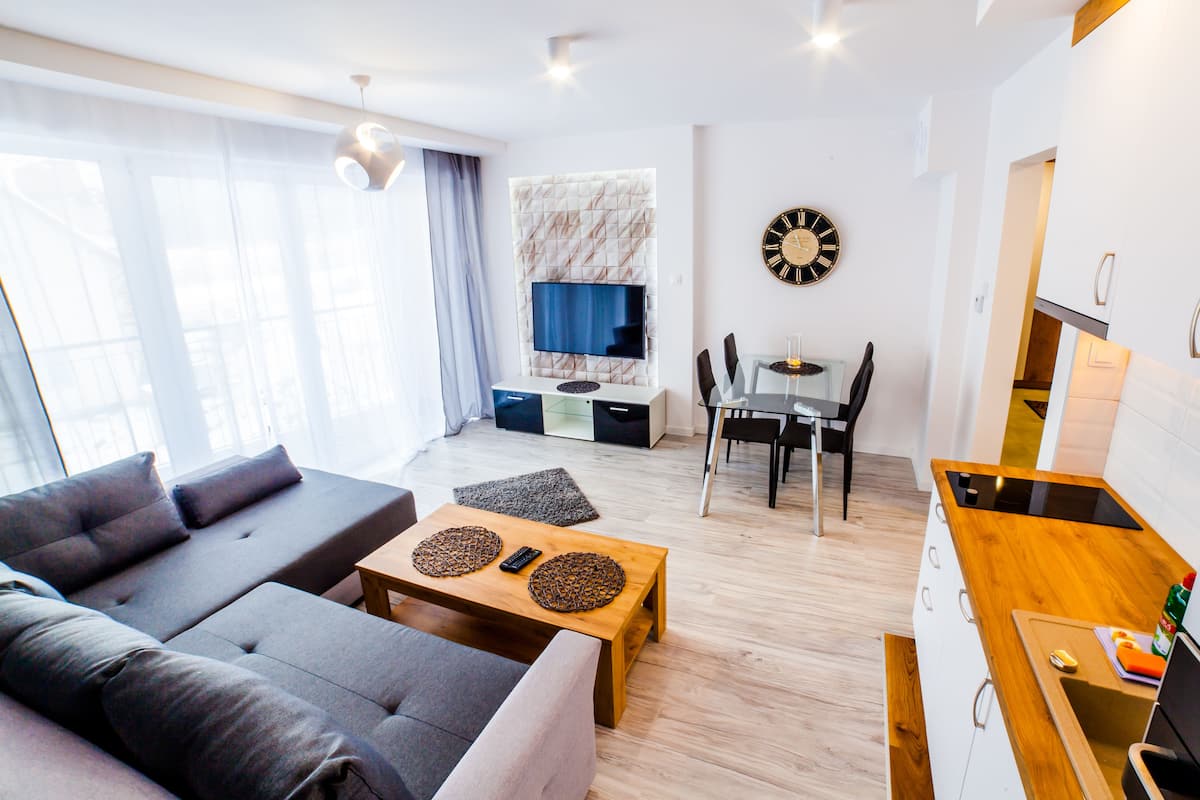 A modern living room with a sofa, coffee table, and a TV mounted on the wall.