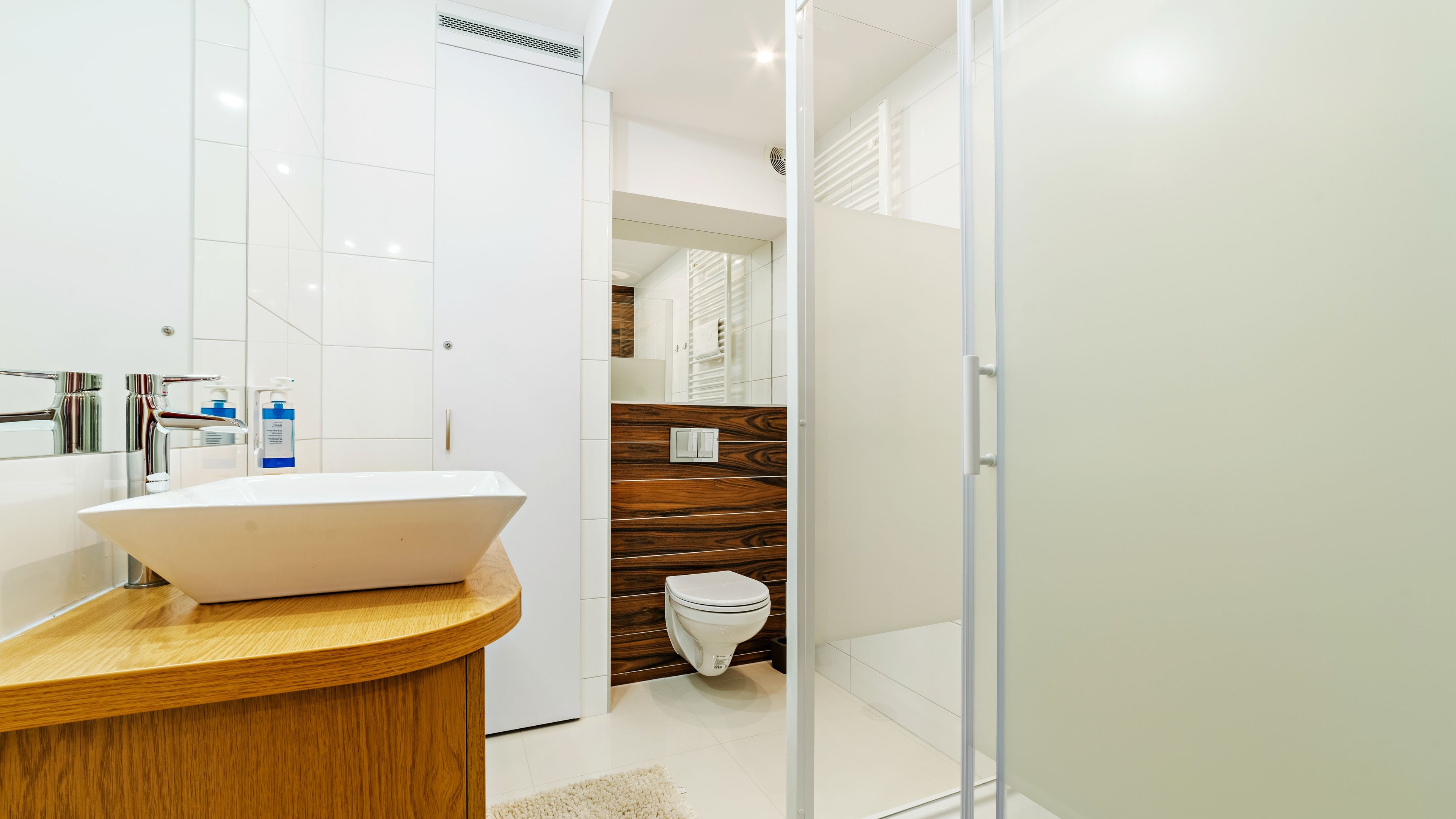 Une salle de bain moderne avec un lavabo blanc, un meuble-lavabo en bois et des toilettes blanches.