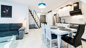Una cocina moderna con armarios blancos, una campana extractora negra y electrodomésticos de acero inoxidable.