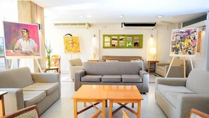 A modern hotel lobby with a grey sofa, wooden coffee table, and wicker chairs. - Hotel Salto Grande (Concordia)
