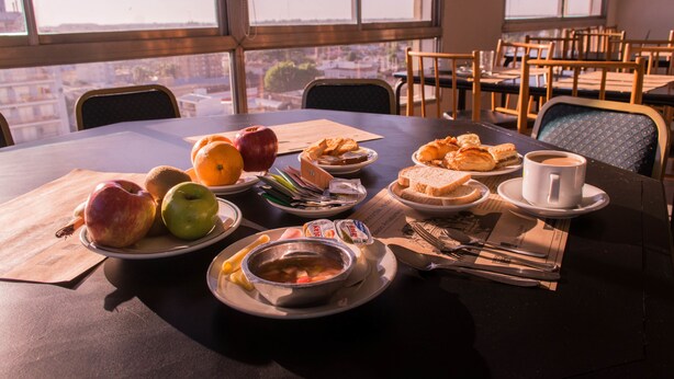 A dining table with various food items, a cup of coffee, and a newspaper. - Hotel Salto Grande (Concordia)
