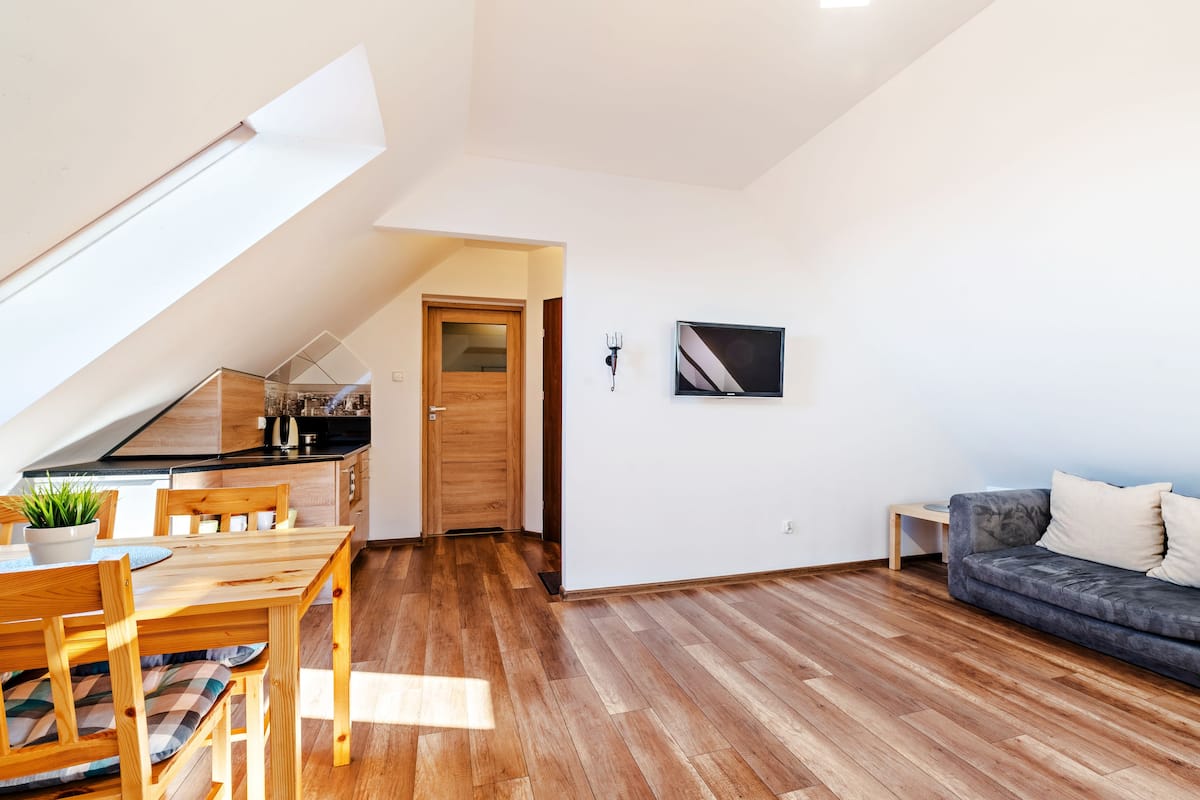 Un espacio moderno para vivir con comedor, un sofá gris y un televisor montado en la pared.