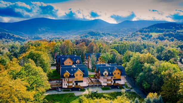 Zona residencial com várias casas, rodeada por vegetação exuberante e montanhas ao fundo.