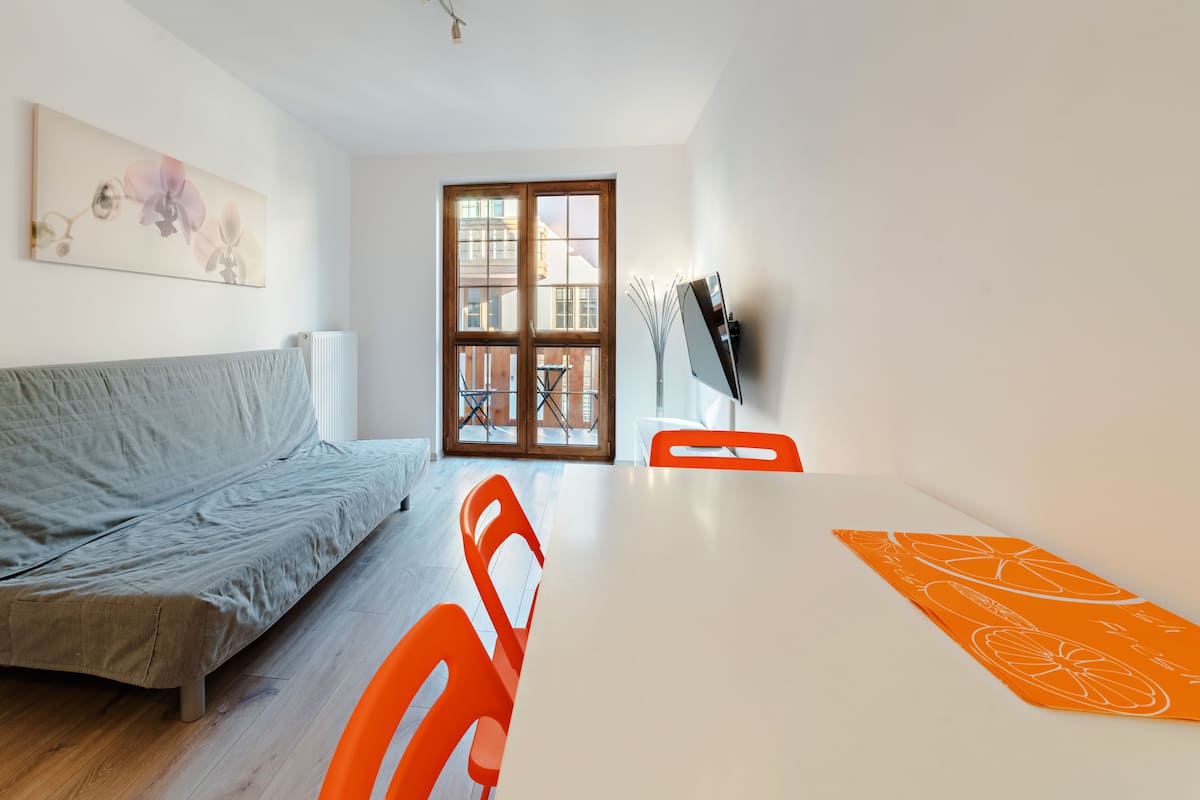 Una sala de estar moderna con un sofá gris, una mesa blanca y una alfombra naranja.