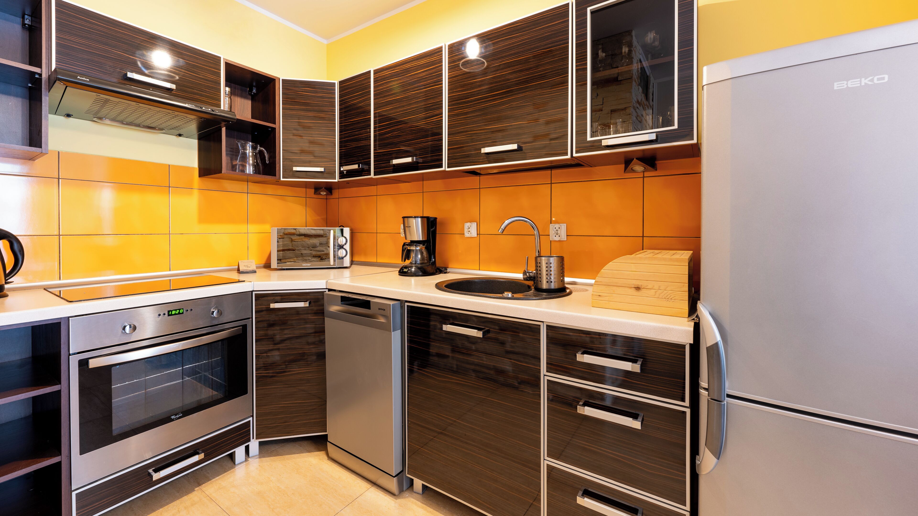 A modern kitchen with built-in appliances, a microwave, coffee maker, and a sink.