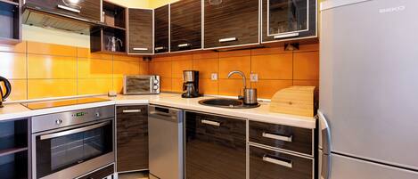 A modern kitchen with built-in appliances, a microwave, coffee maker, and a sink.