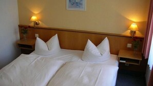 A double bed with white linens, two bedside tables with lamps, and a framed picture on the wall. - Hotel Goldene Sonne (Annaberg-Buchholz)