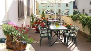 An outdoor patio with a table and chairs, surrounded by potted plants and flowers. - Hotel Goldene Sonne (Annaberg-Buchholz)