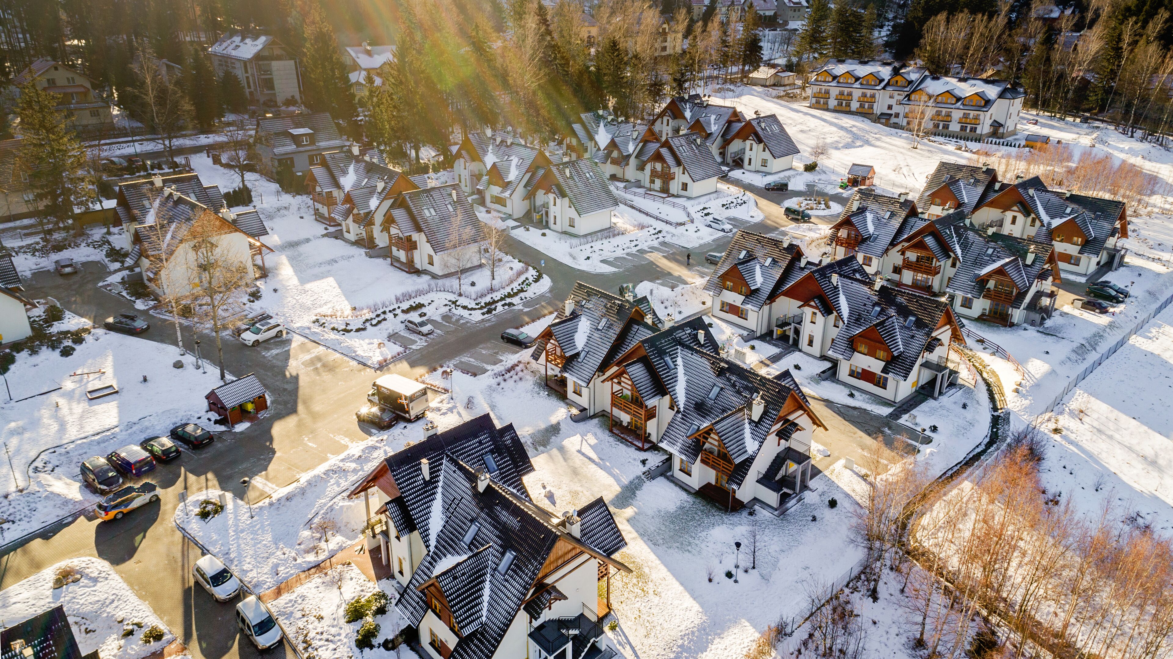 Ett snötäckt bostadsområde med flera hus som har sluttande tak och träfasader.