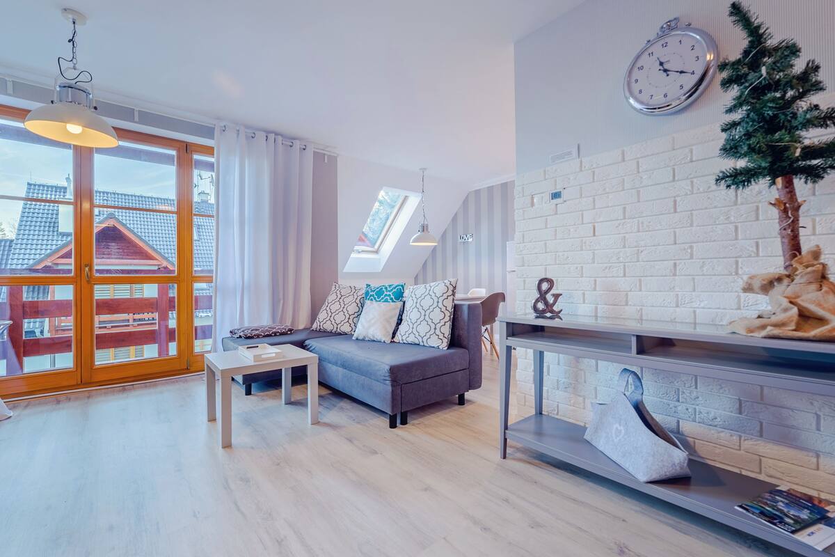 Ein modernes Wohnzimmer mit einer Couch, einem Couchtisch, einem Kamin und einer Wanduhr.